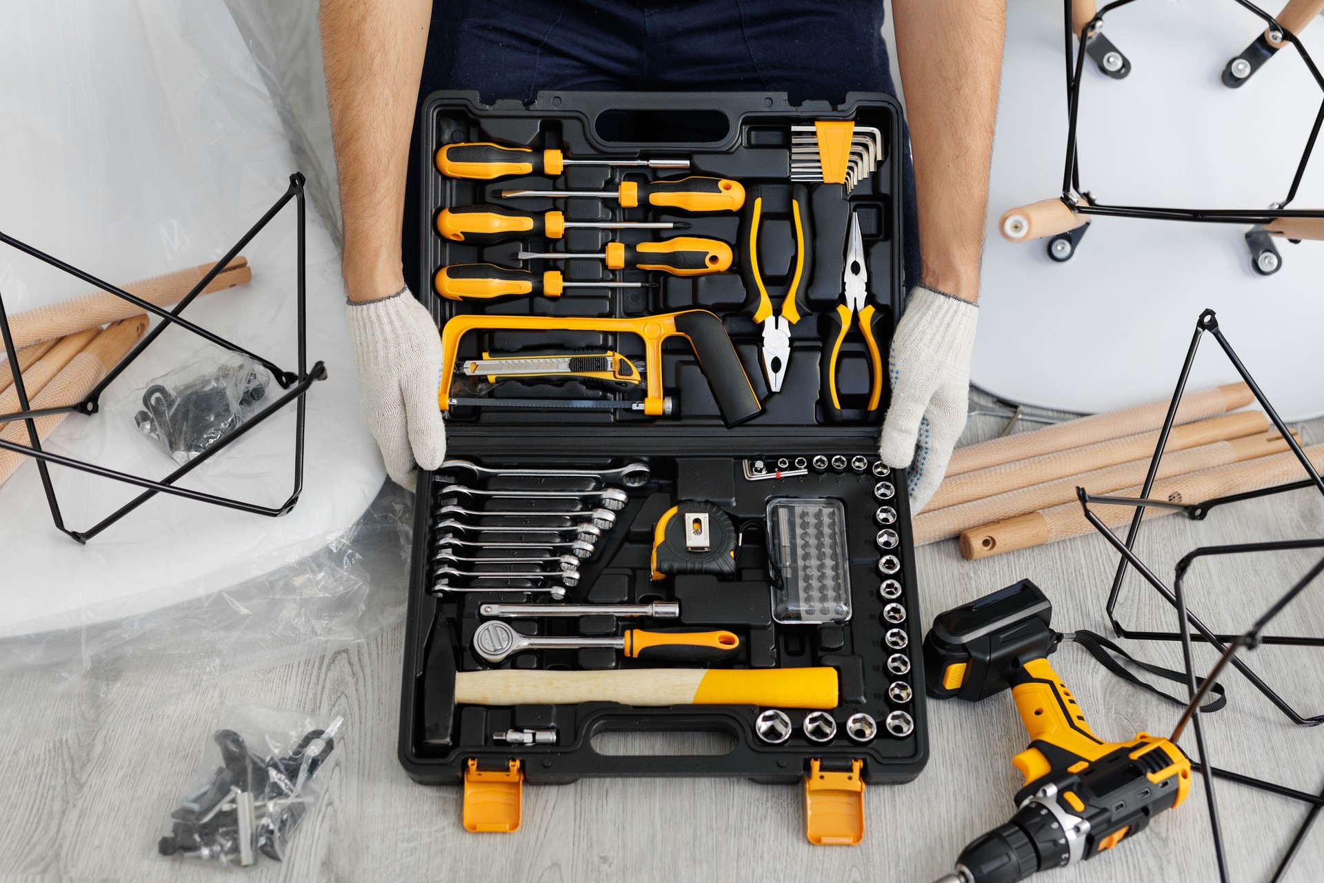 A male craftsman holds a set of tools in a suitcase on the floor in close-up.